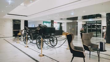 A modern lobby with a classic carriage, marble flooring, and contemporary seating.