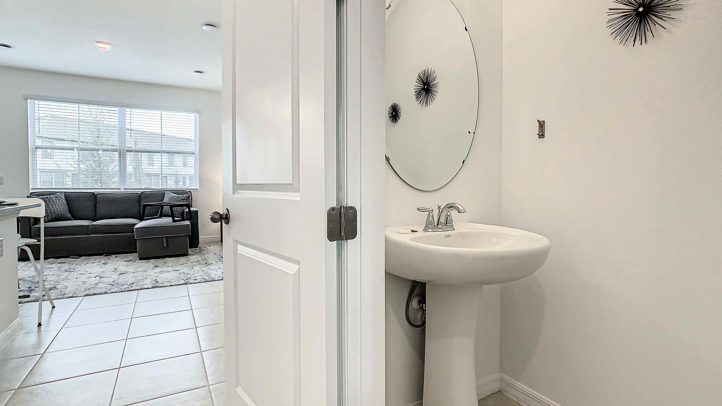 A modern bathroom with a white sink, a round mirror, and decorative wall art.