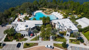 An aerial view of a resort with a swimming pool, landscaped areas, and a parking lot.