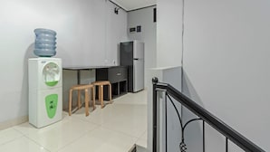 Cozinha moderna com dispensador de água, dois banquinhos e uma geladeira.