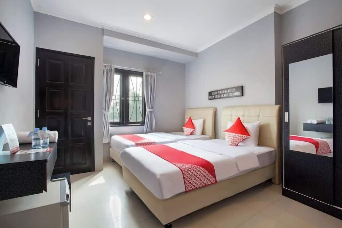 Habitación de hotel con dos camas, un escritorio, un espejo y una ventana con cortinas.