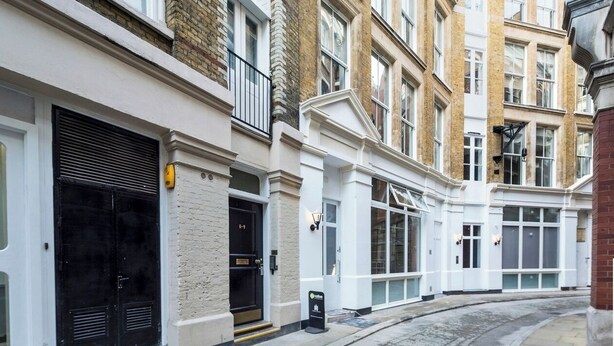 A row of traditional brick townhouses with white facades, large windows, and a curved driveway.