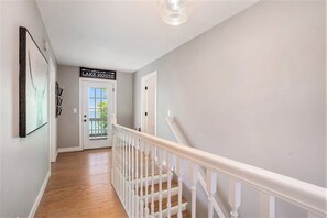 A hallway with a staircase, a door labeled 'LAKE HOUSE,' and a framed picture on the wall.