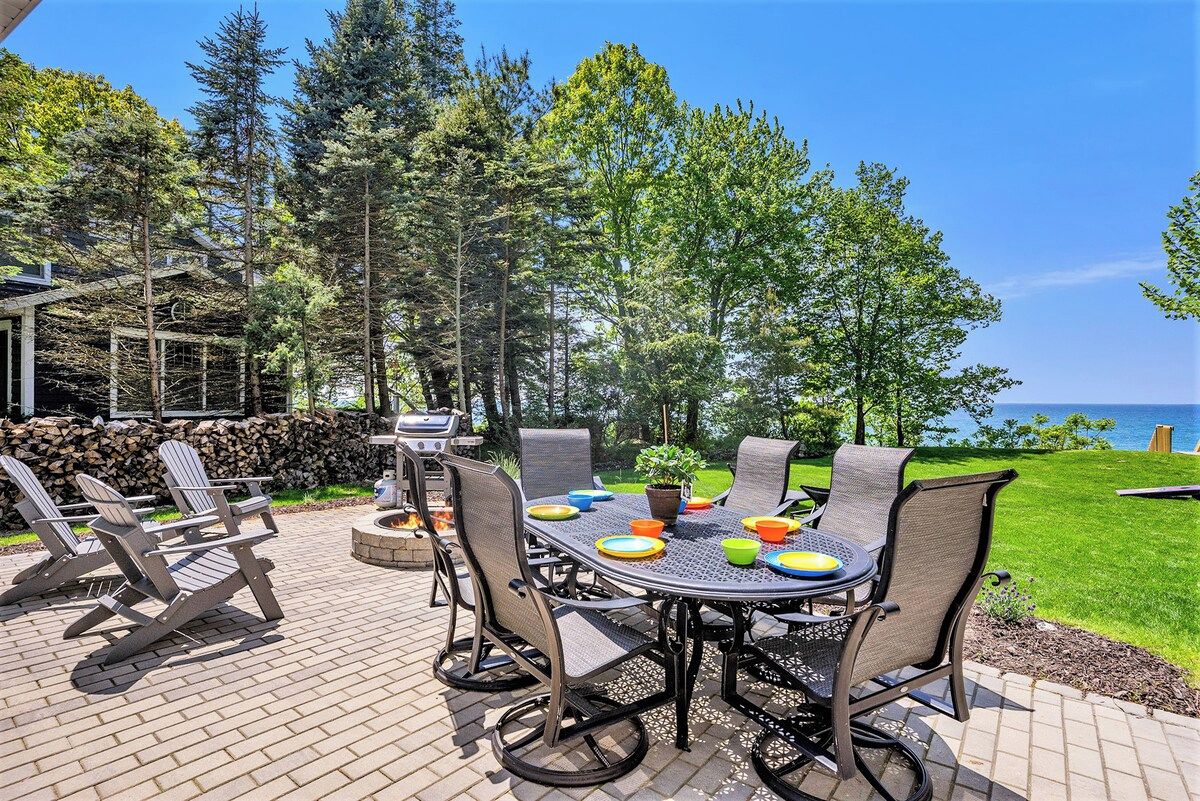 Une terrasse extérieure avec une table et des chaises, entourée d’arbres et offrant une vue sur l’océan.
