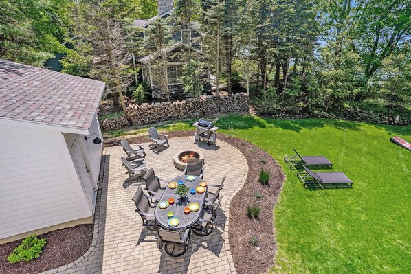 A patio with a fire pit, outdoor seating, and a grill area.
