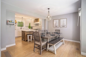 A modern kitchen with white cabinets, a wooden island, and a dining area with a dark wood table and chairs.