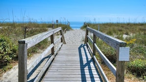 Un paseo marítimo de madera que conduce a una playa con vista clara al océano.