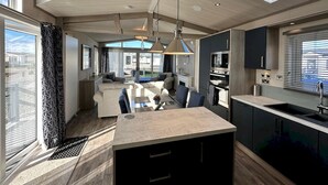 A modern kitchen with a central island, built-in appliances, and large windows offering city views. - Lodge No 20 | Hot Tub |  Stewart's Resort Cameron (Cameron)