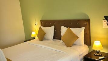 Una habitación de hotel con una cama, dos mesitas de noche y una lámpara.