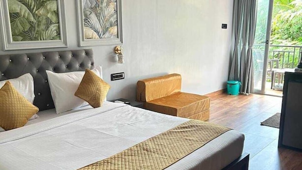 Ein Hotelzimmer mit einem großen Bett, einer Sitzecke und einem Balkon mit Vorhängen.