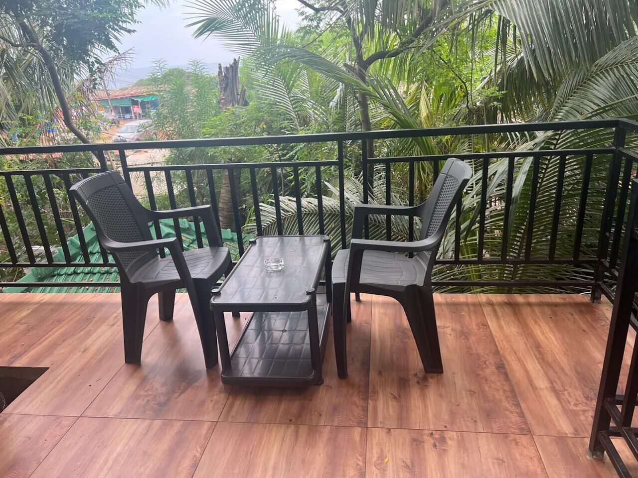 A wooden deck with a metal railing, two chairs, and a table.