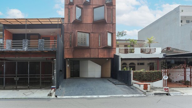 A modern building with a unique geometric facade, a gated entrance, and a clear sky. - Hotel O Pondok Indah Near Gandaria City Formerly Odori Residence (Jakarta)