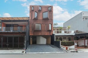 Un edificio moderno con una fachada geométrica distintiva, una entrada portonada y cielo despejado.