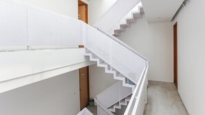 A white, multi-level staircase with a modern design, leading to different floors. - Hotel O Pondok Indah Near Gandaria City Formerly Odori Residence (Jakarta)