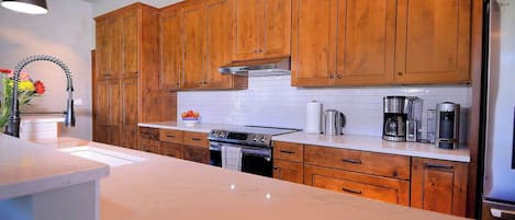 Une cuisine avec des meubles en bois, un réfrigérateur en acier inoxydable, une cuisinière à gaz et une machine à café.