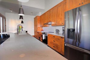 A modern kitchen with wooden cabinets, stainless steel appliances, and a marble countertop.