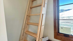 Una scala di legno in una stanza con una finestra che si affaccia su un paesaggio innevato.