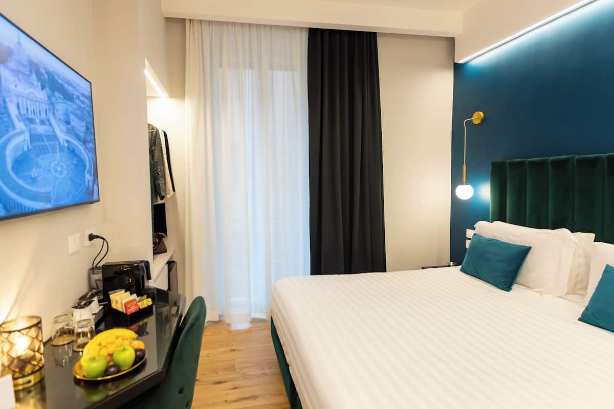 A hotel room with a bed, a desk with a computer, a TV, and a fruit bowl.