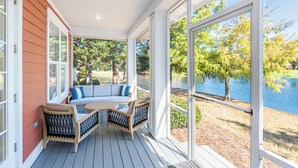 A covered outdoor seating area with a view of a lake and trees. - Two Golf Carts ~ Lake & Golf Course Views (Miramar Beach)