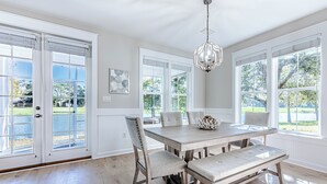 A dining area with a wooden table, cushioned chairs, and a chandelier. - Two Golf Carts ~ Lake & Golf Course Views (Miramar Beach)