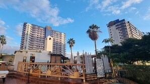 Een hotel met een opvallend Hard Rock bord, meerdere verdiepingen en een dak terras met palmbomen en terrasmeubilair.