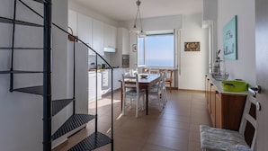 Une cuisine spacieuse avec un coin repas, un escalier et une vue sur la mer.