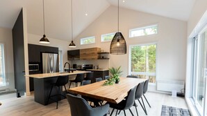 A modern kitchen with a central island, black chairs, and pendant lighting.