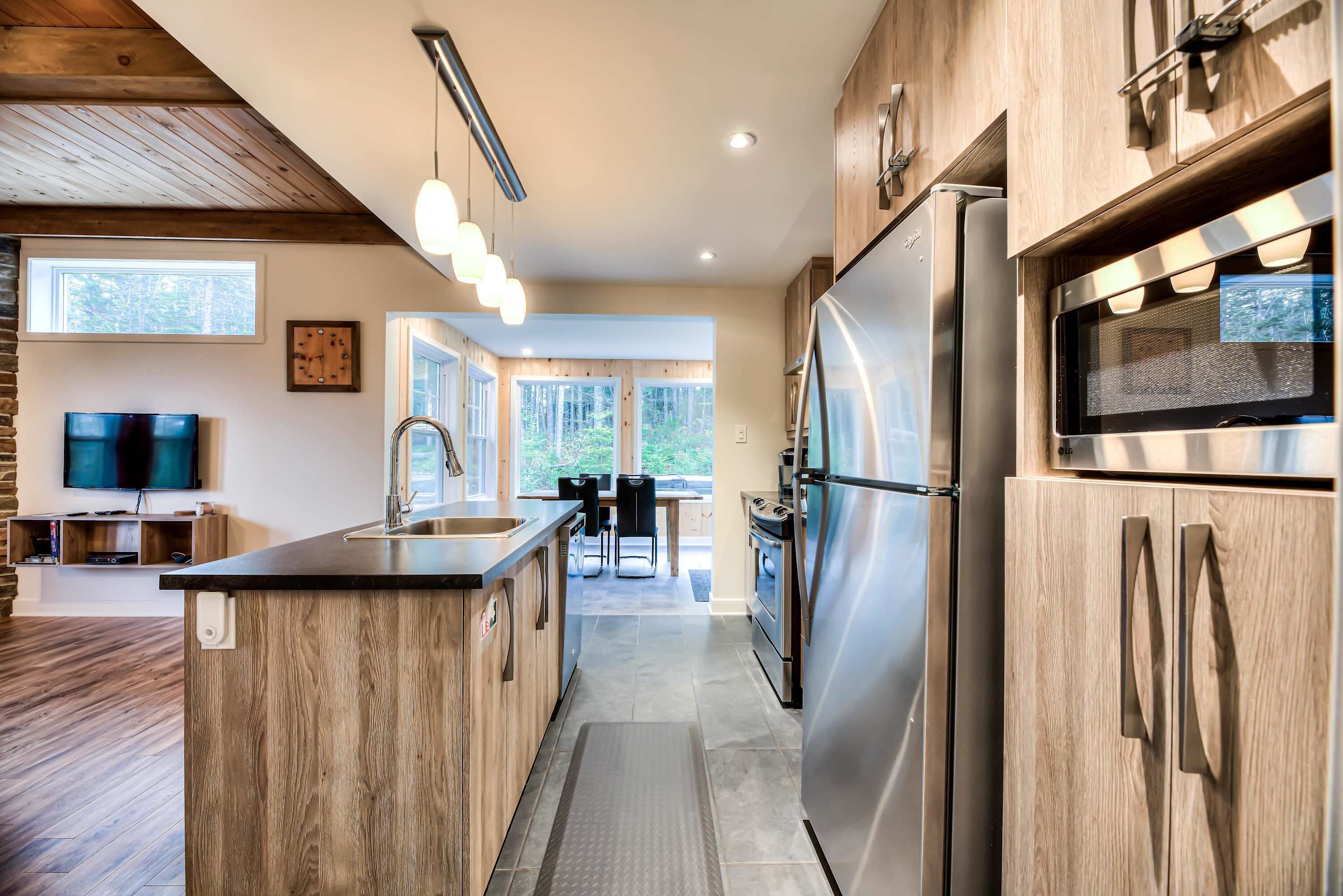 A modern kitchen with wooden cabinetry, stainless steel appliances, and a central island.