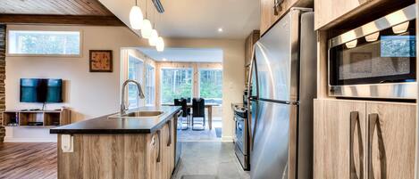 A modern kitchen with wooden cabinetry, stainless steel appliances, and a central island.