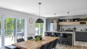 Una cocina moderna con una isla central, taburetes de bar y una mesa de comedor con sillas.