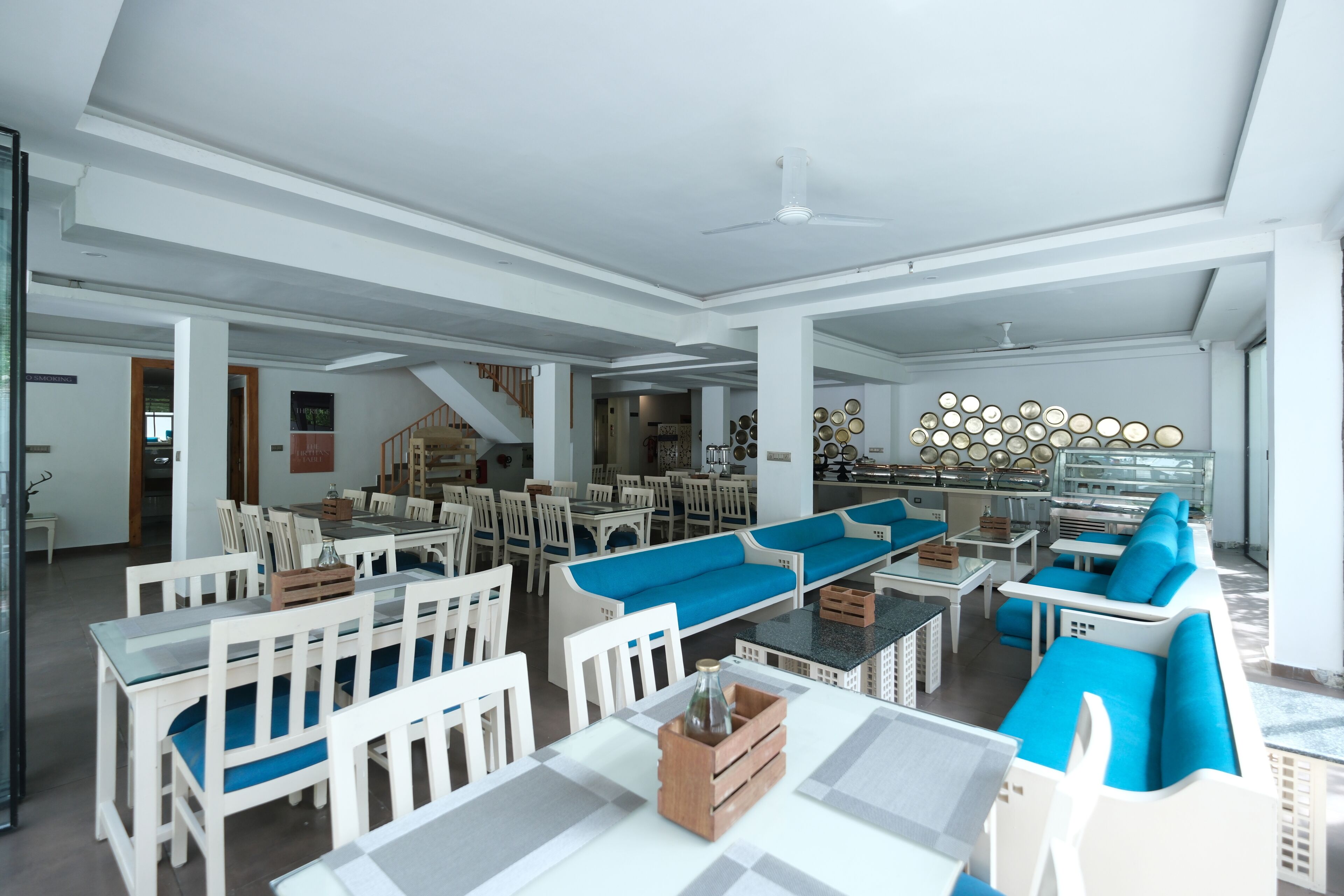 A spacious indoor area with multiple seating arrangements, including tables and chairs, and a large blue sofa.