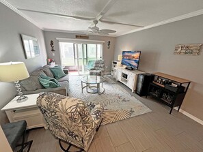 A living room with a sofa, armchair, coffee table, TV, and a bar area.
