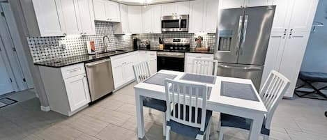 A modern kitchen with white cabinetry, a central island, and stainless steel appliances.
