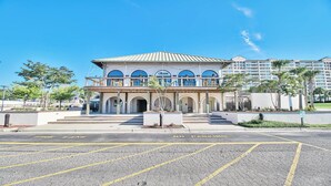 A hotel with a central courtyard, multiple balconies, and a parking lot with no parking signs. - 133 River Crossing - Barefoot Resort Rentals (North Myrtle Beach)