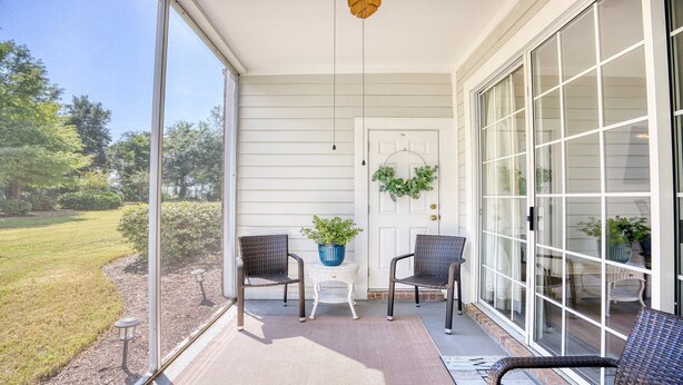 Une véranda abritée avec deux fauteuils en osier, une petite table et une plante en pot.