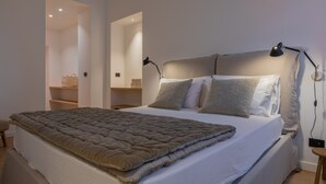 A neatly made bed with a brown quilt, two bedside lamps, and a headboard with a light fixture. - Le Giacose Design 2 by Wonderful Italy (Turin)
