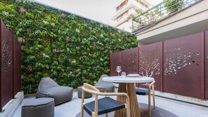 An outdoor seating area with a round table and chairs, surrounded by a vertical garden wall. - Le Giacose Design 2 by Wonderful Italy (Turin)