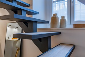 A modern staircase with a minimalist design, leading to a room with a large window and two decorative vases on the sill. - Le Giacose Design 1 by Wonderful Italy (Turin)