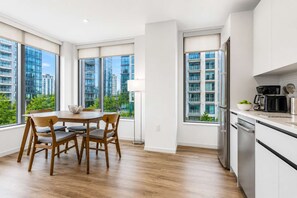 Una cocina moderna con comedor, ventanas amplias y vistas a edificios altos.