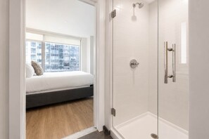 Un dormitorio con cama, ventana y zona de ducha.