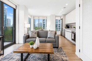 Un apartamento moderno con un sofá gris, una mesa de centro de madera y una zona de cocina.