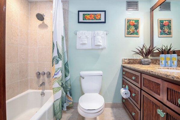 Une salle de bain équipée d’une baignoire, de toilettes et d’un meuble-lavabo avec un miroir et un porte-serviettes.