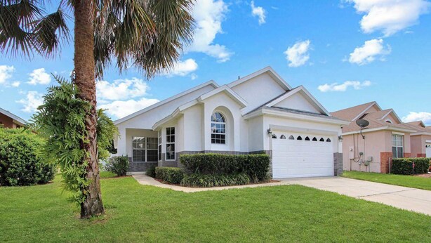 A single-story house with a white exterior, a garage, and a well-maintained lawn. - Amazing Game Room Salt Water Pool 10 Min to Disney (Kissimmee)