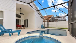 A swimming pool with a hot tub, surrounded by a covered patio with lounge chairs and a table. - Amazing Game Room Salt Water Pool 10 Min to Disney (Kissimmee)