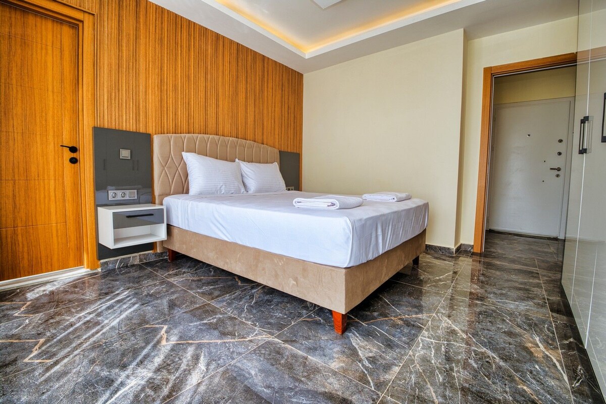 A hotel room with a bed, a nightstand, a wooden wardrobe, and a door.