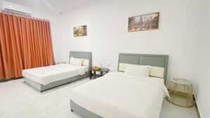 Ένα δωμάτιο ξενοδοχείου με δύο κρεβάτια, ένα μικρό τραπέζι και ένα κλιματιστικό που είναι τοποθετημένο στον τοίχο.