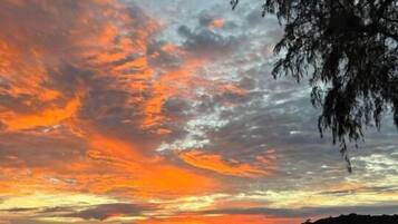 A sunset view from a wooden deck with a railing overlooking the ocean.