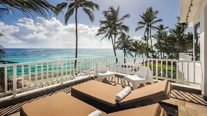 A balcony with lounge chairs and a view of the ocean and palm trees. - KITE BEACH HOTEL Ocean View Penthouse with 2 Decks Cabarete (Cabarete)