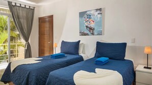 A hotel room with two beds, a painting on the wall, a window with curtains, and a door. - KITE BEACH HOTEL Ocean View Penthouse with 2 Decks Cabarete (Cabarete)