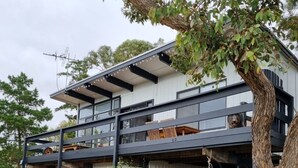 A modern two-story house with a balcony, a tree in front, and a parked car. - Straight to the Point - Sea views from balcony, dog friendly! (Pine Point)